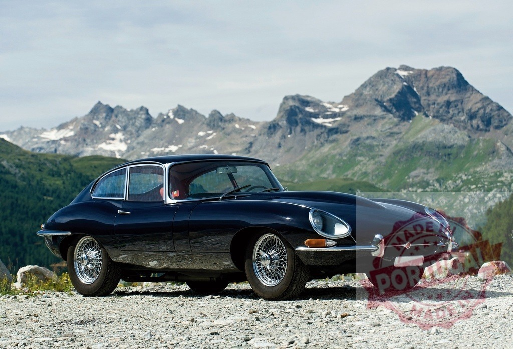 Jaguar E-Type classic car travelling through Alps mountains | Dark blue Jaguar E-Type coupe parked on a gravel roadside with mountains in background - Realisiert mit Pictrs.com