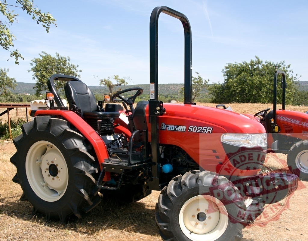 Branson 5025R red tractor parked outdoors | Red Branson 5025R compact tractor standing in a dry field during daytime - Realized with Pictrs.com