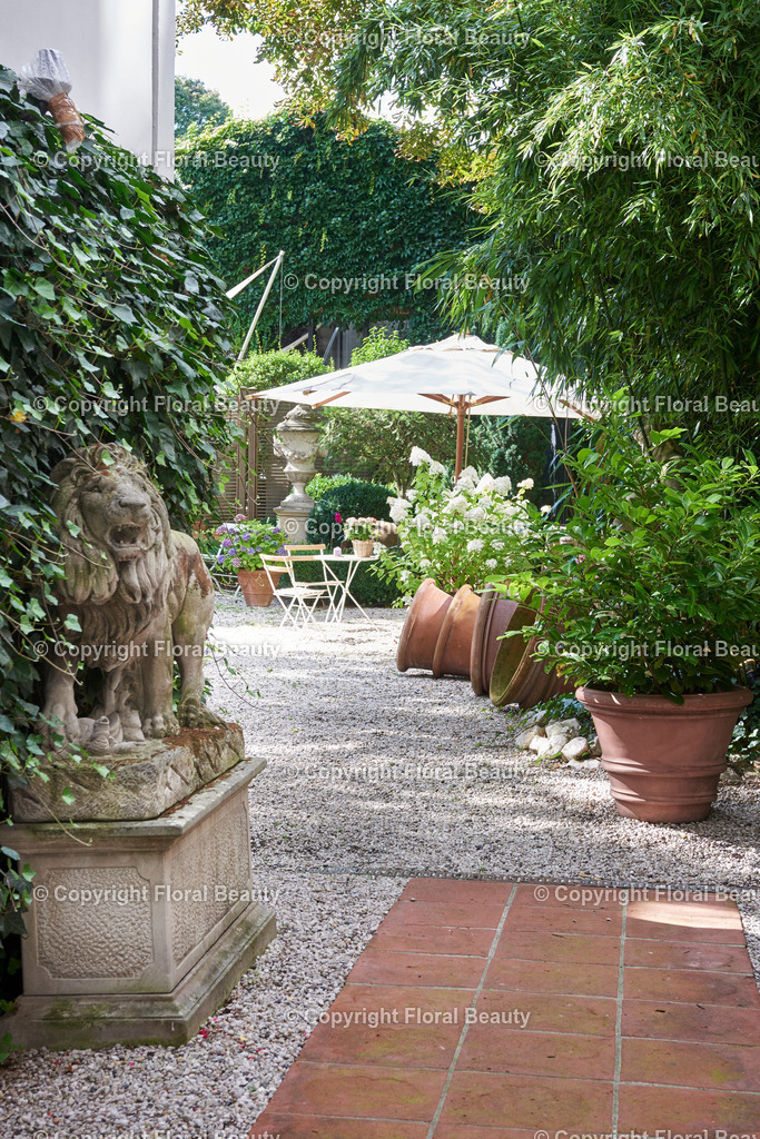 Mediterraner Stadtgarten | Städtischer Garten mit Löwenstatue und antiken Tontöpfen, Sonnenschirm und Hortensie - Realisiert mit Pictrs.com