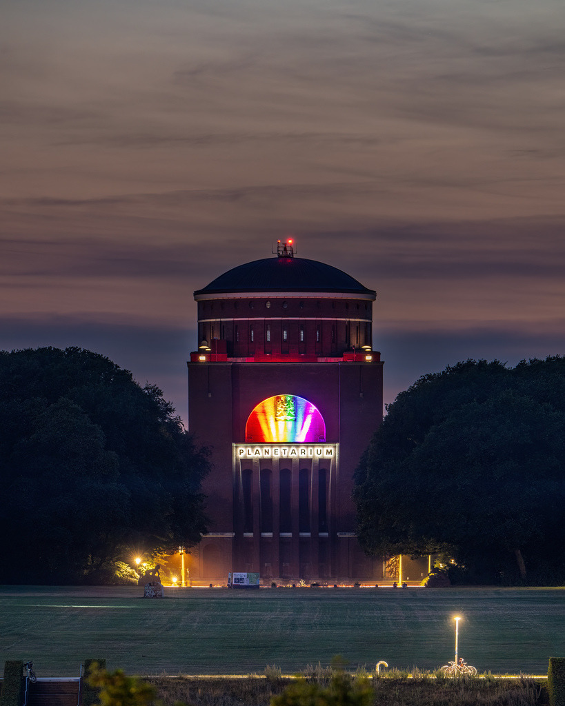 Hamburg unter dem Abendhimmel | Das beleuchtete Planetarium Hamburg in Regenbogenfarben vor einem atmosphärischen Abendhimmel über dem Stadtpark. - Realisiert mit Pictrs.com