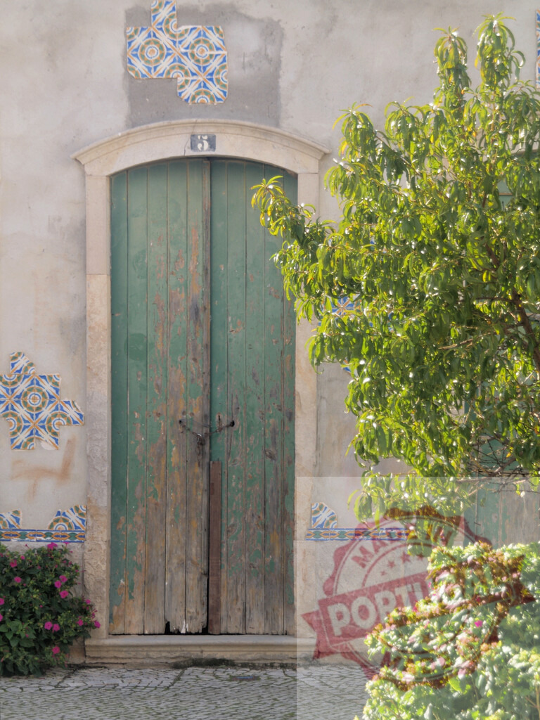 Weathered green wooden door with traditional Portuguese tiles | Old green wooden door with azulejo tiles on a rustic building facade in Portugal - Realisiert mit Pictrs.com