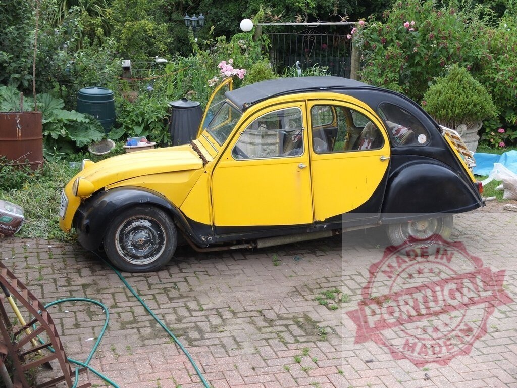 Citroën 2CV parked in a garden showing its iconic design | Classic Citroën 2CV parked in a peaceful garden setting, highlighting its unique and recognizable design - Realisiert mit Pictrs.com