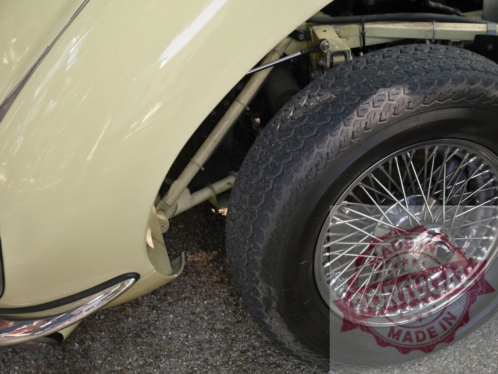 Jaguar vintage car wire wheel and suspension detail | Cream colored Jaguar classic car showing wire wheel, tire, and suspension components - Realisiert mit Pictrs.com