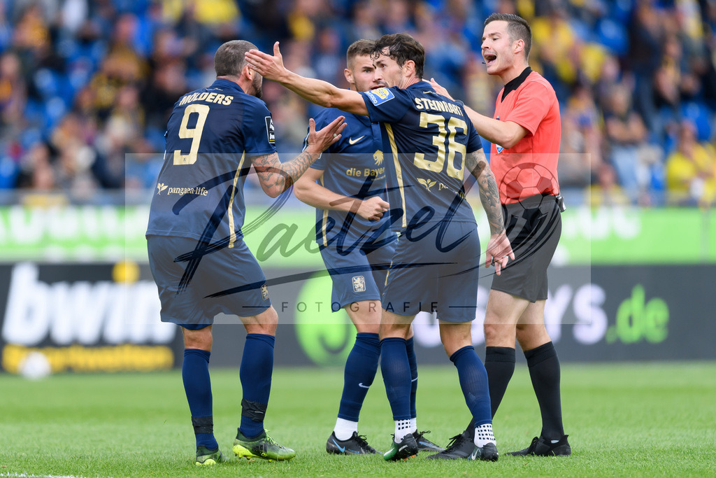 EBSTSV20210828_053 | Fussball, Herren: . Spieler von TSV 1860 Muenchen beschweren sich beim Schiedsrichter Harm Osmers beim Spiel der 3. Liga zwischen Eintracht Braunschweig und TSV 1860 Muenchen im Eintracht-Stadion am 28.08.2021 in Braunschweig, Deutschland.DFB / DFL REGULATIONS PROHIBIT ANY USE OF PHOTOGRAPHS AS IMAGE SEQUENCES AND/OR QUASI-VIDEO. - Realisiert mit Pictrs.com
