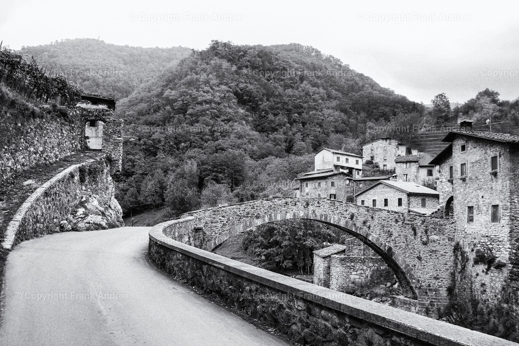 Fabbriche di Vergemoli Toskana | Blick entlang einer Straße auf eine alte Steinbrücke in Fabbriche di Vergemoli Toskana - Realisiert mit Pictrs.com