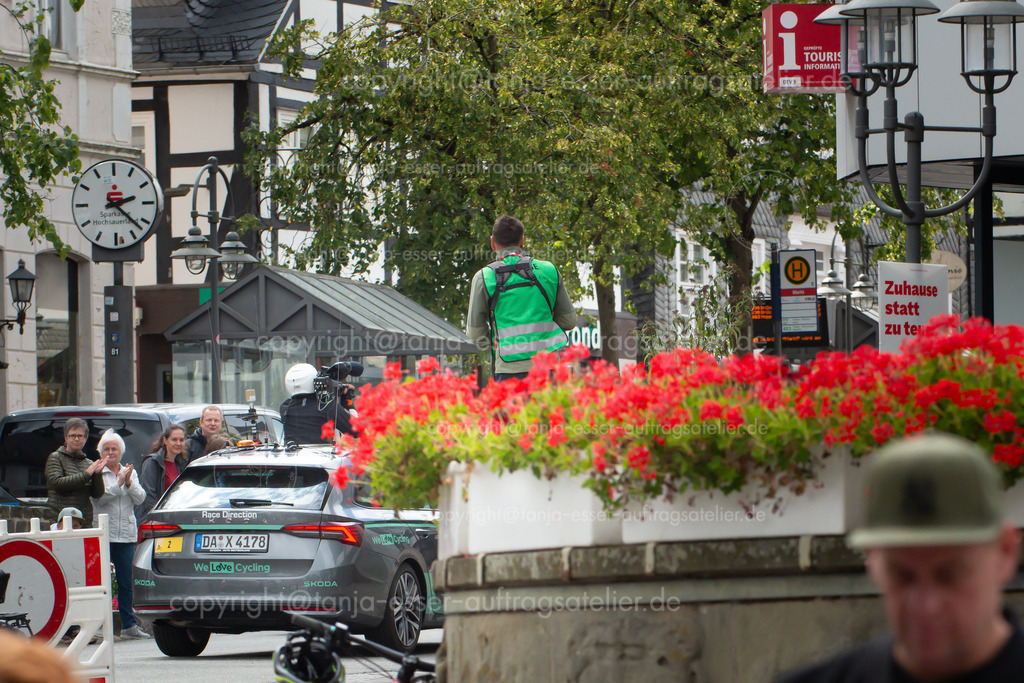 Deutschlandtour Rennleitung D | Brilon, Nordrhein-Westfalen, Deutschland – 23. August 2025: Internationales Straßenradrennen, Lidl Deutschlandtour, in der Stadt. Fernsehreporter und Rennleitung verfolgen es live im Fernsehen.