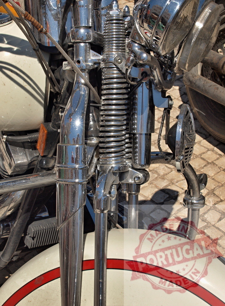 Vintage motorcycle detailing chrome springer forks | Vintage motorcycle front end showing chrome springer forks and headlight - Realized with Pictrs.com