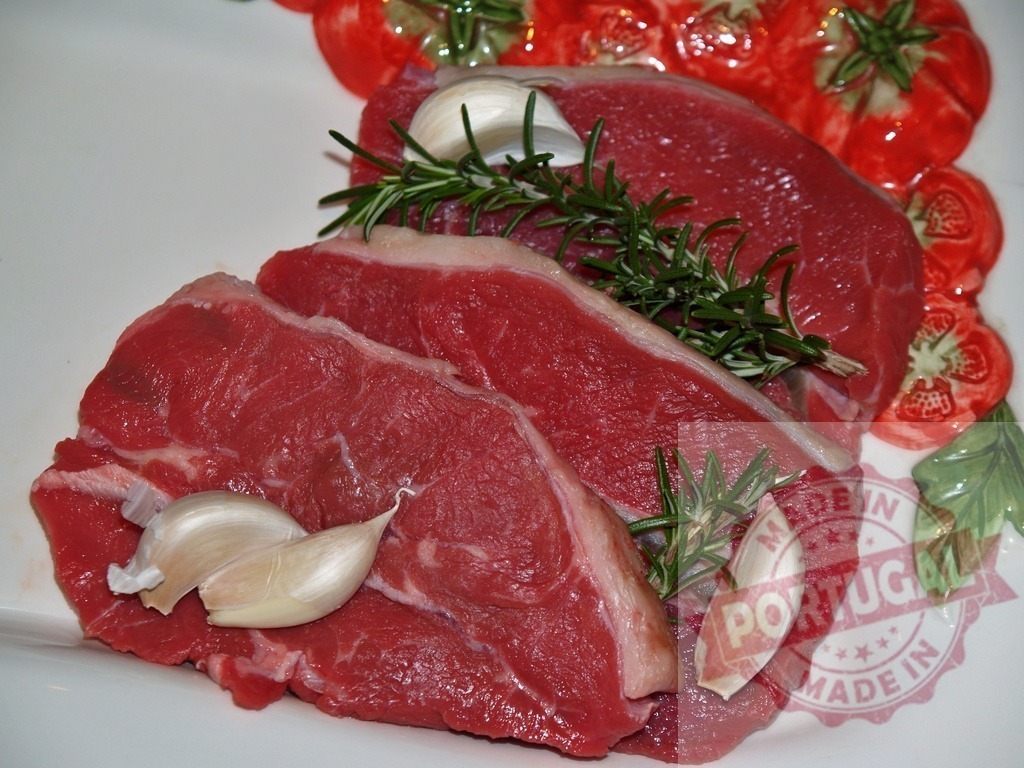 Raw beef steaks with garlic and rosemary | Raw beef steaks prepared with fresh garlic cloves and rosemary sprigs on a plate - Realized with Pictrs.com