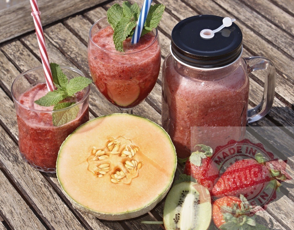 Fresh fruit smoothies with melon, strawberries, and kiwi | Fresh fruit smoothies on a rustic wooden table with melon, strawberries, kiwi, and mint leaves - Realisiert mit Pictrs.com