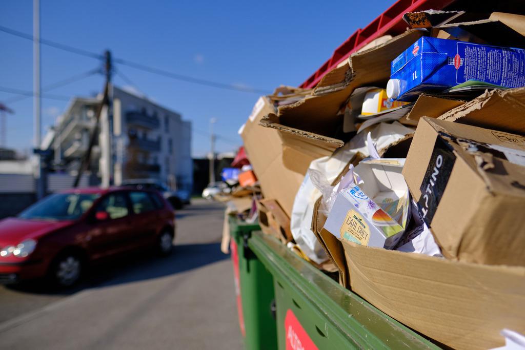 Container mit Karton und Papier neben einer Straße | Wien, Austria - March 17, 2021: Container mit Karton und Papier neben einer Straße mit Wohnanlage. - Realisiert mit Pictrs.com
