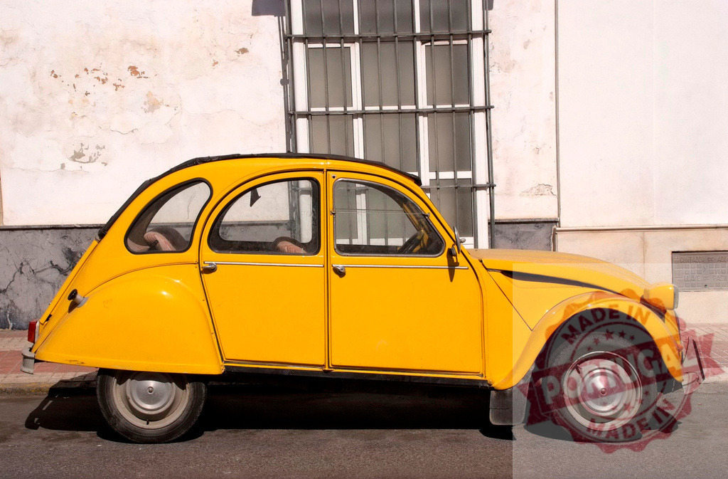Classic yellow Citroën 2CV parked on the street in front of a white wall | Citroën 2CV, a classic French car, parked on a sunny street in front of a weathered white wall with a barred window - Realized with Pictrs.com