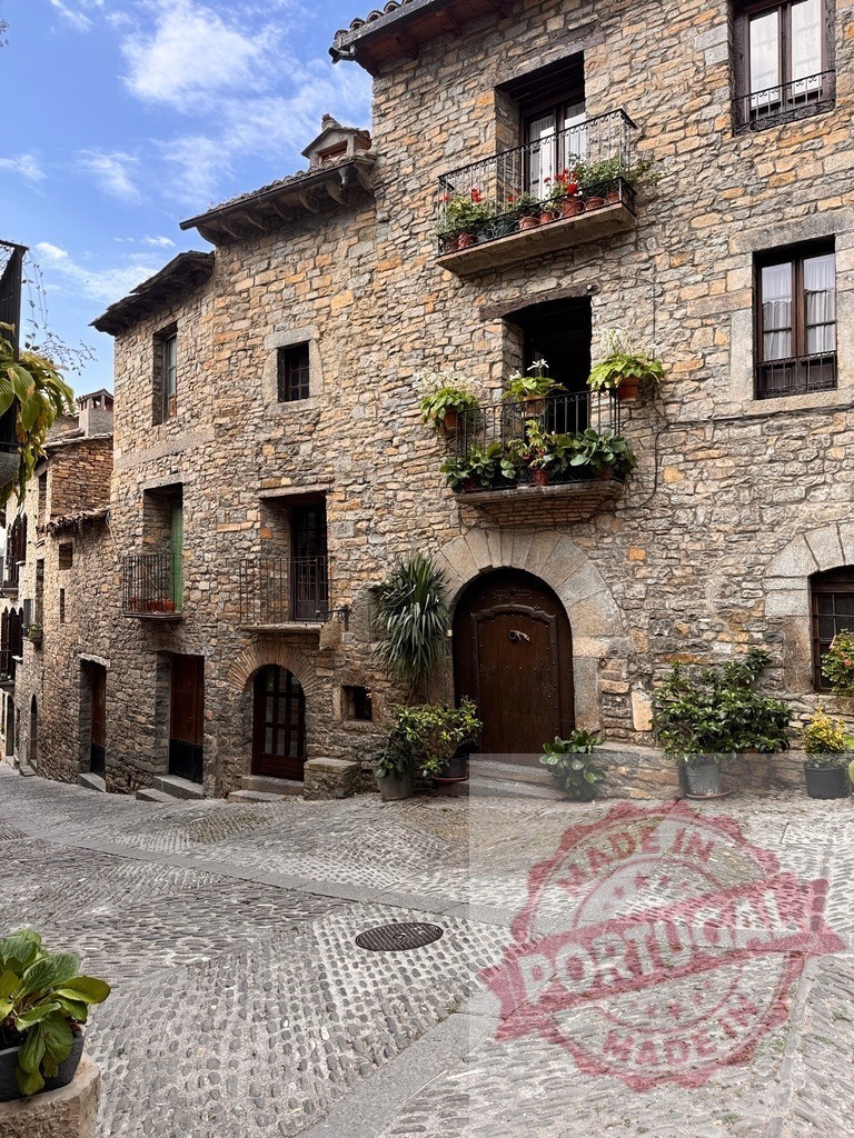 Aínsa medieval village street with cobblestones and balconies | Aínsa stone buildings showing traditional architecture with plant-filled balconies - Realisiert mit Pictrs.com
