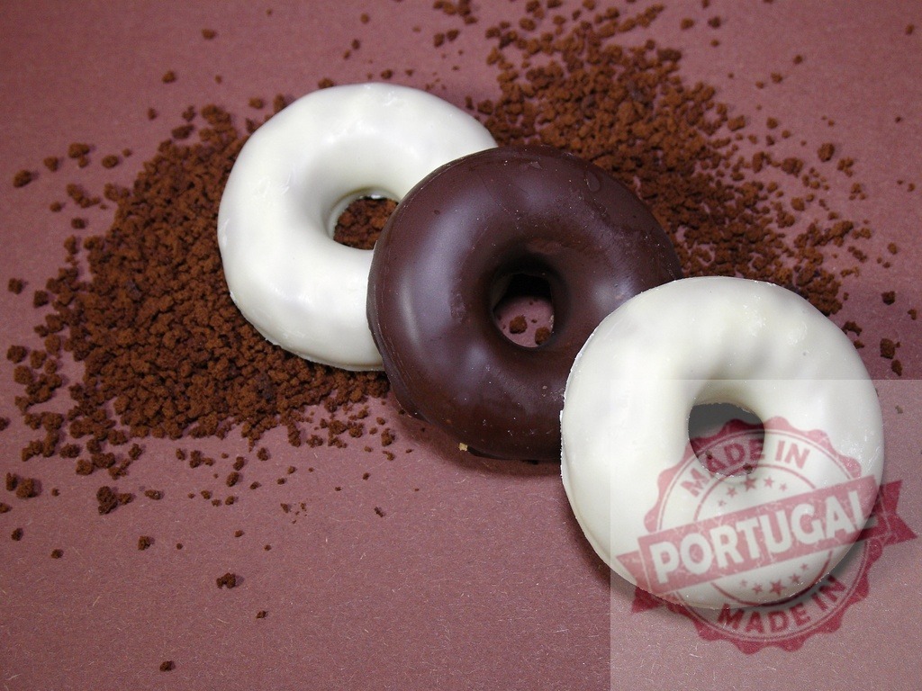 Chocolate and white glazed donuts with coffee grounds | Sweet donuts with chocolate and white glaze resting on instant coffee granules - Realized with Pictrs.com