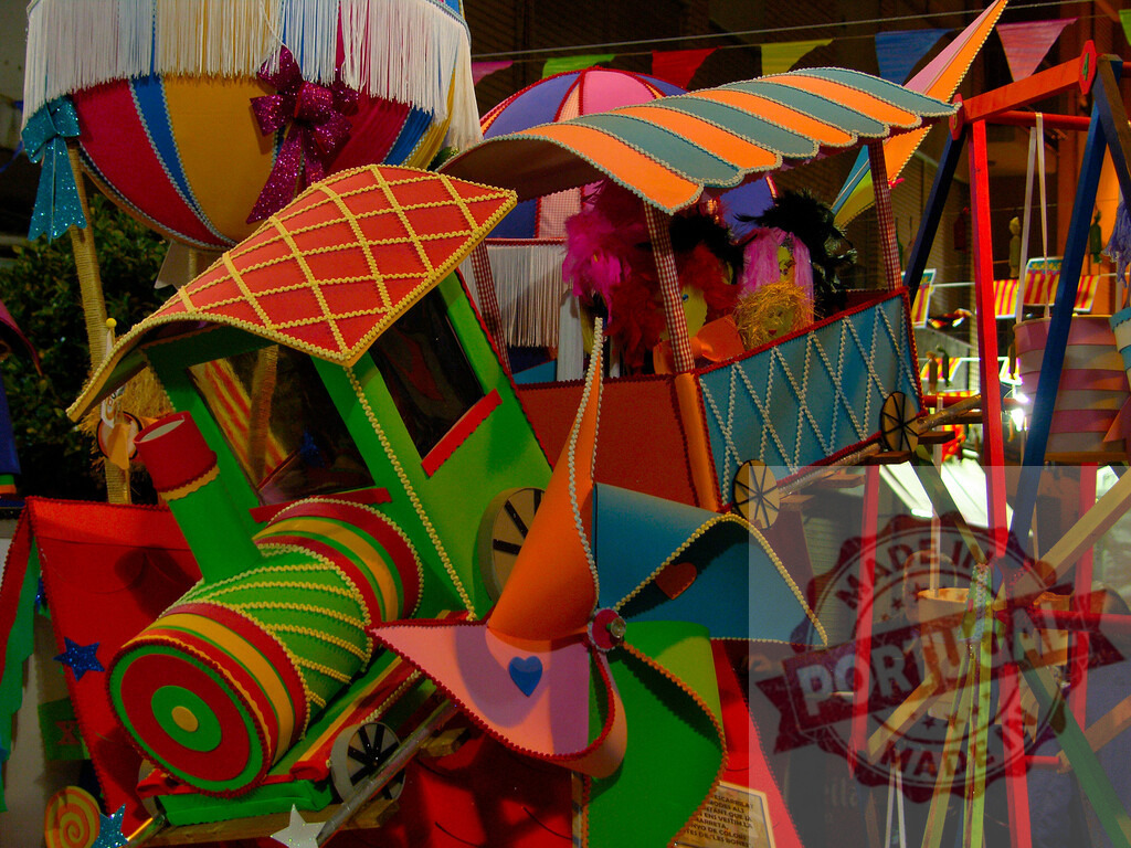 Colorful carnival float representing a fun toy parade. Fallas Fiestas Communidad Valenciana | Elaborate carnival float decorated with bright colors, toy train, and a Ferris wheel - Realized with Pictrs.com