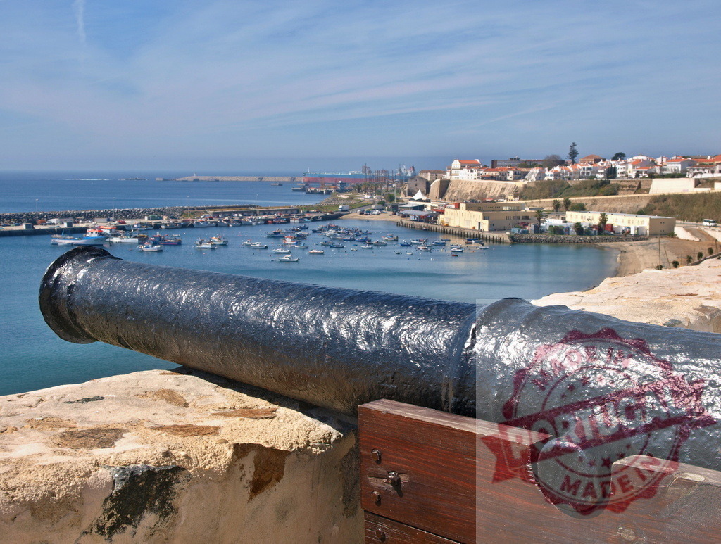 Old cannon pointing at Sines harbor and town | Historic cannon protecting the coastal town of Sines with its bustling harbor and boats - Realized with Pictrs.com