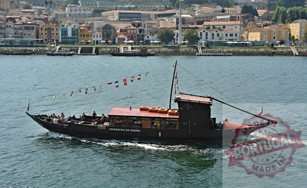 Rabelo boat cruising Douro River in Porto, Portugal. Porto - Portugal | Rabelo boat carrying tourists sailing on the Douro River with Ribeira buildings in background - Realized with Pictrs.com