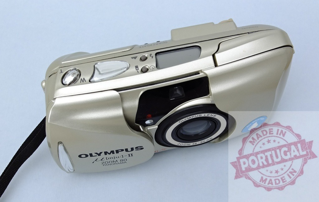 Olympus Mju II Zoom 80 film camera against light blue background | Olympus Mju II Zoom 80 point and shoot film camera, vintage photography technology - Realized with Pictrs.com