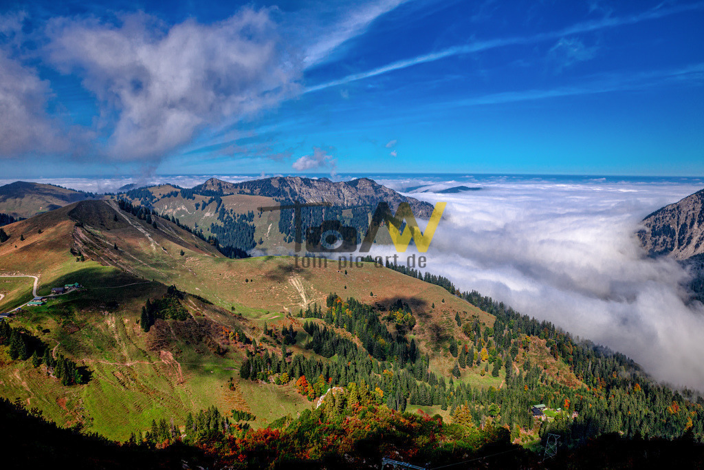 Tief und schwer hängen die Wolken im Tegernseer Tal--Berge | Das Bild zeigt die spektakuläre Lage der Tegernseer Hütte (1650 m) zwischen den Gipfeln von Roßstein (1698 m) und Buchstein (1701 m). Die Hütte wird oft als "Adlernest" bezeichnet, da sie exponiert auf dem Grat liegt. Sie ist ein beliebtes Ziel für Wanderer und Kletterer in den Bayerischen Voralpen. Die Hütte bietet Übernachtungsmöglichkeiten und ist in der Regel von Mai bis November bewirtschaftet. Vom Standort der Hütte aus hat man einen 360-Grad-Panoramablick auf umliegende Berge wie die Blauberge, den Guffert und den Hirschberg.  - Realisiert mit Pictrs.com