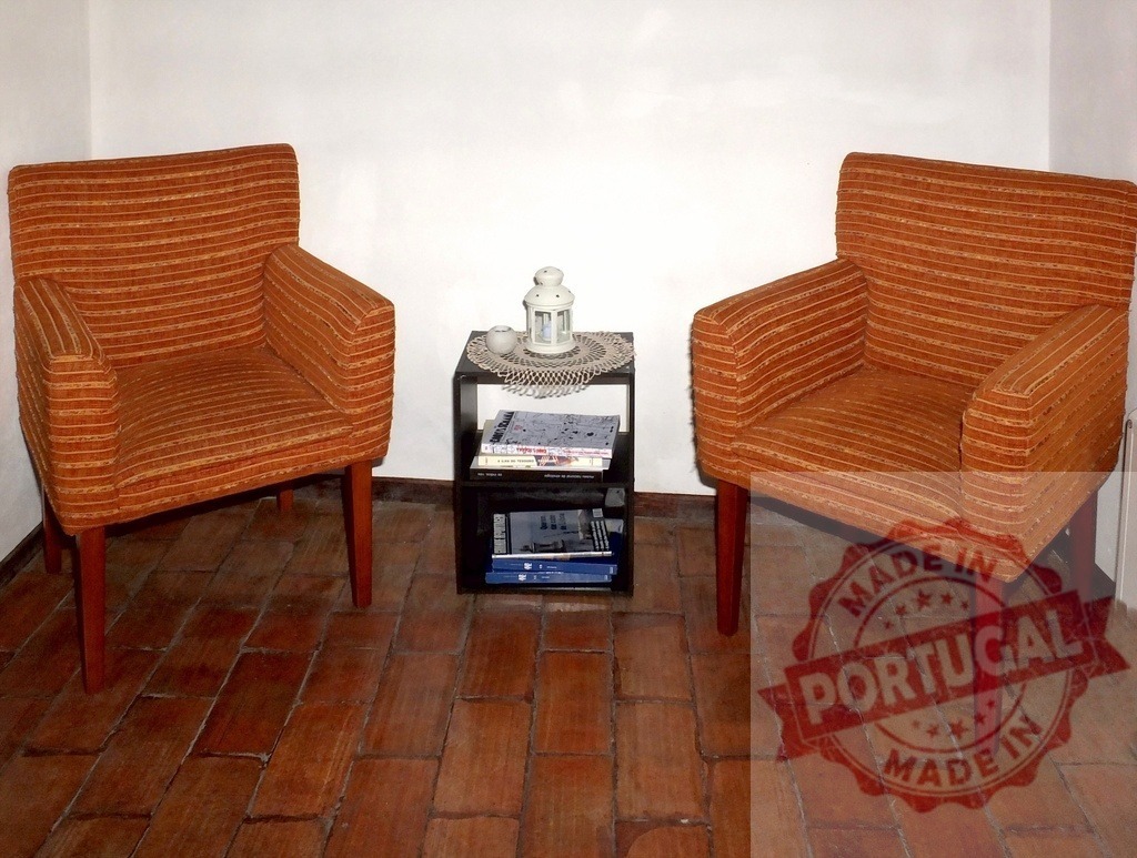 Two orange armchairs filling a corner living space | Two inviting orange armchairs flank a modern side table with a lantern and magazines - Realisiert mit Pictrs.com
