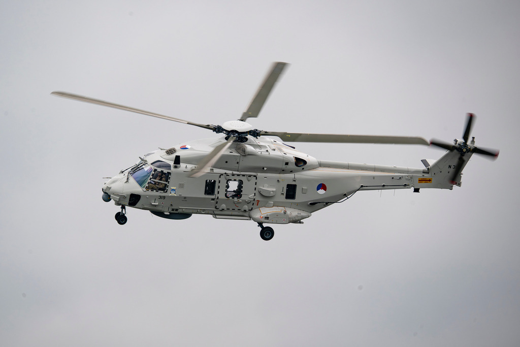 "Sealion" niederländische Marineflieger | Eine detaillierte Profilaufnahme eines grauen NH90-Transporthubschraubers der niederländischen Marine vor einem neutralen, bewölkten Himmel. Gut zu erkennen sind die Kennnummer "319", das Hoheitsabzeichen sowie technische Details wie das Fahrwerk und die Sensorik an der Nase des Luftfahrzeugs. - Realisiert mit Pictrs.com