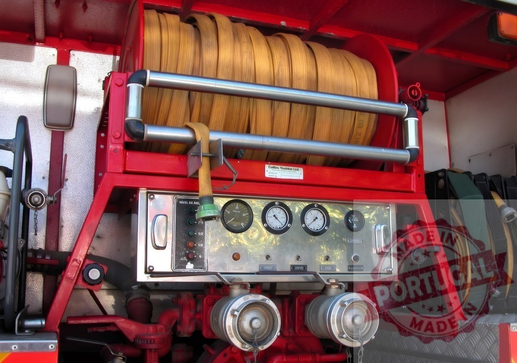 Fire engine hose reel and control panel displaying equipment | Fire engine pump panel with gauges, switches, and a yellow hose reel for emergency services - Realized with Pictrs.com