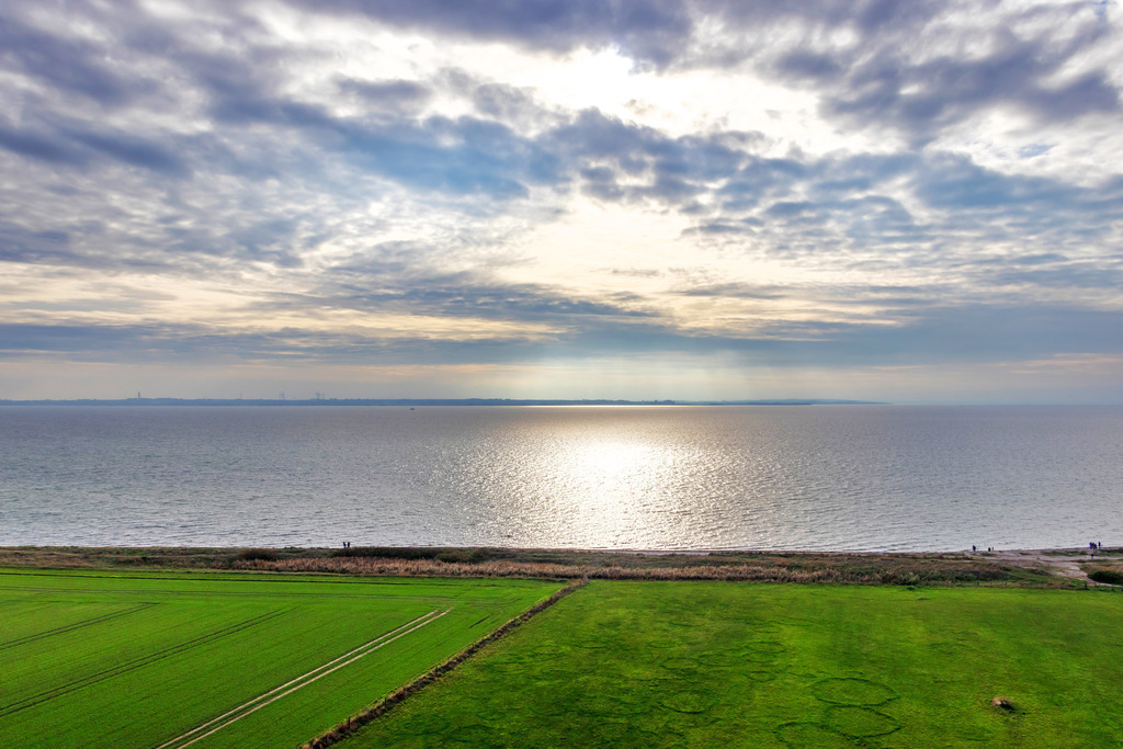 Leinwand: Schöne Lichtstimmung auf Fehmarn | Sanfte Farben und ein harmonisches Abendlicht – dieses Wandbild vermittelt Ruhe und Gelassenheit. Die weitläufige Landschaft mit dem grünen Feld im Vordergrund und der sanften Spiegelung der Sonne auf der Ostsee erzeugt eine friedliche Atmosphäre, die perfekt für medizinische Einrichtungen geeignet ist. Das Motiv schafft eine entspannte Kulisse für Wartezimmer, Behandlungsräume oder Empfangsbereiche und trägt dazu bei, Patienten in einer angenehmen Umgebung willkommen zu heißen. - Realisiert mit Pictrs.com