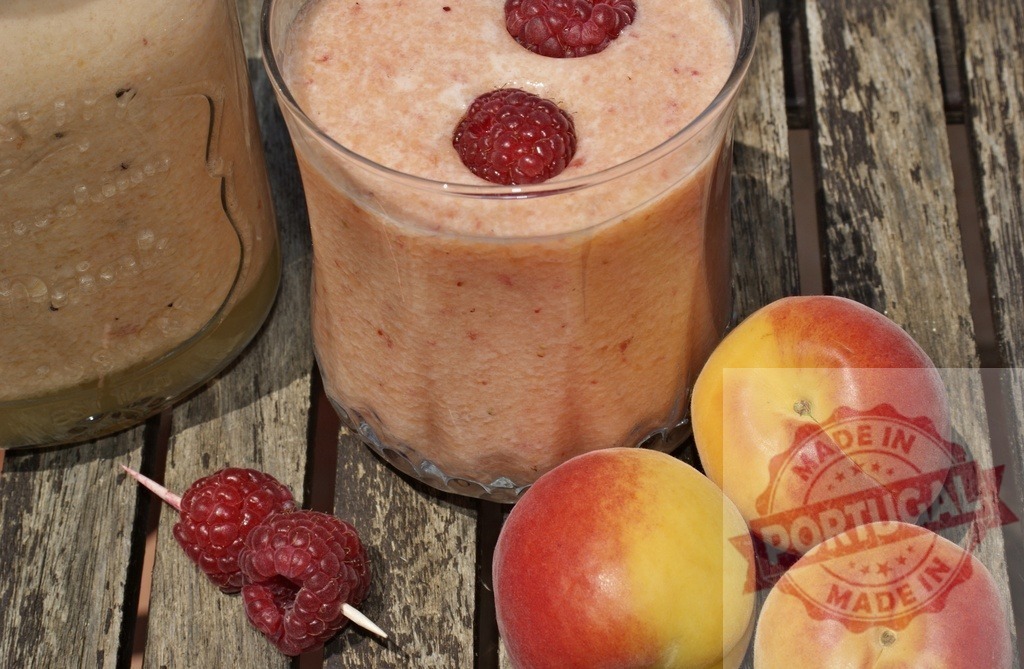Fresh peach and raspberry smoothie on wooden table | Peach and raspberry smoothie on a rustic wooden table with fresh fruit in sunlight - Realisiert mit Pictrs.com