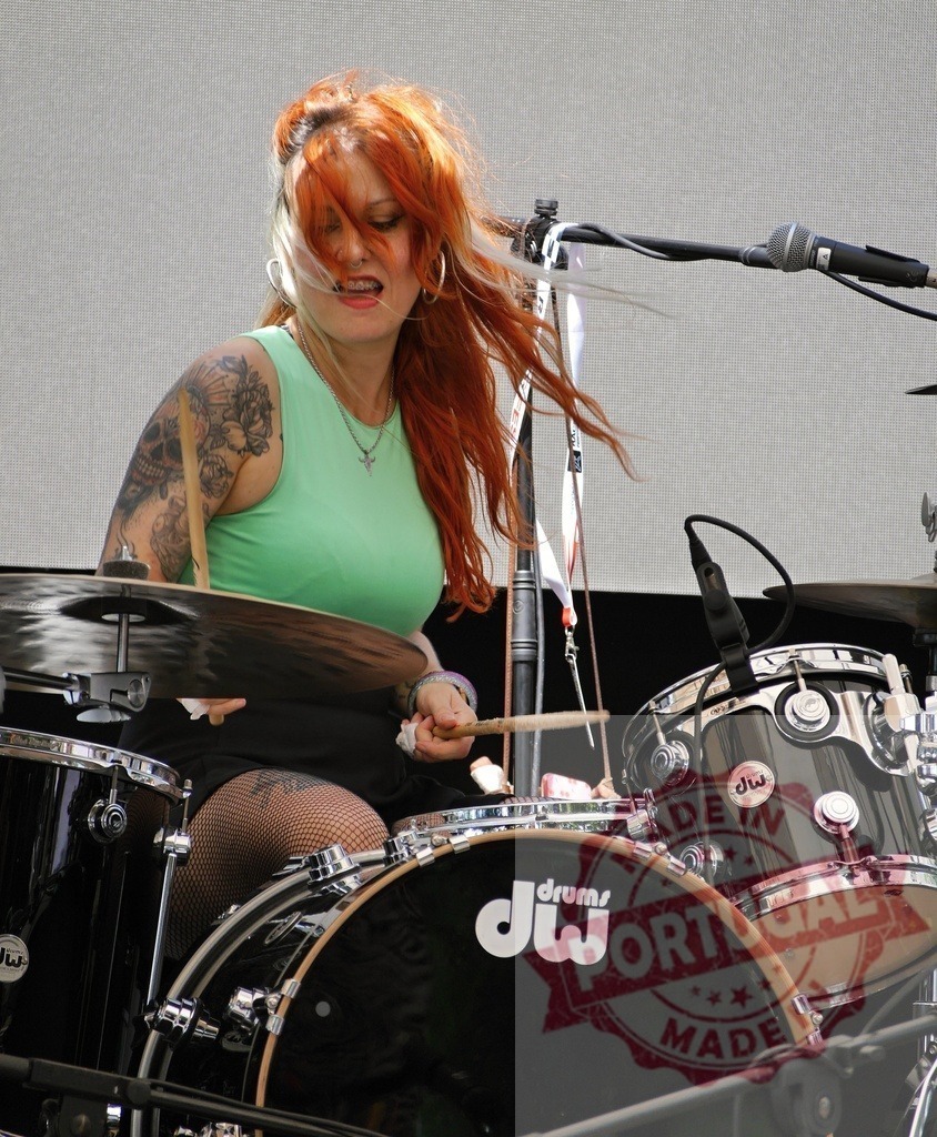 Redhead woman drummer playing drums during concert | Woman drummer with red hair and tattoos performing live on stage - Realisiert mit Pictrs.com