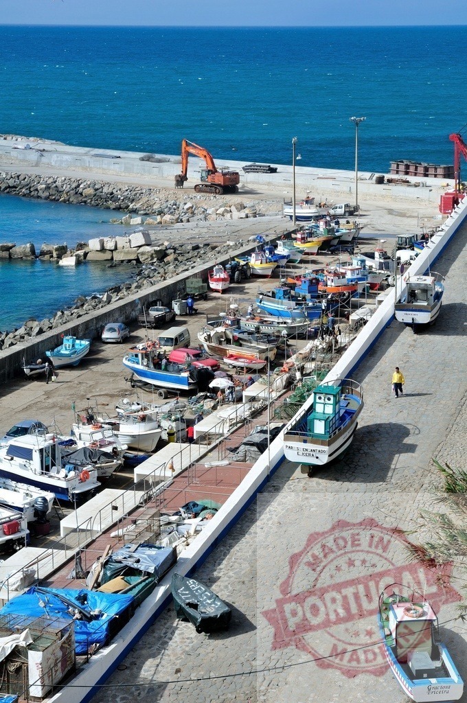 Working fishing port with small boats and excavator | Small fishing boats parked in a harbor with a construction excavator near the sea - Realized with Pictrs.com