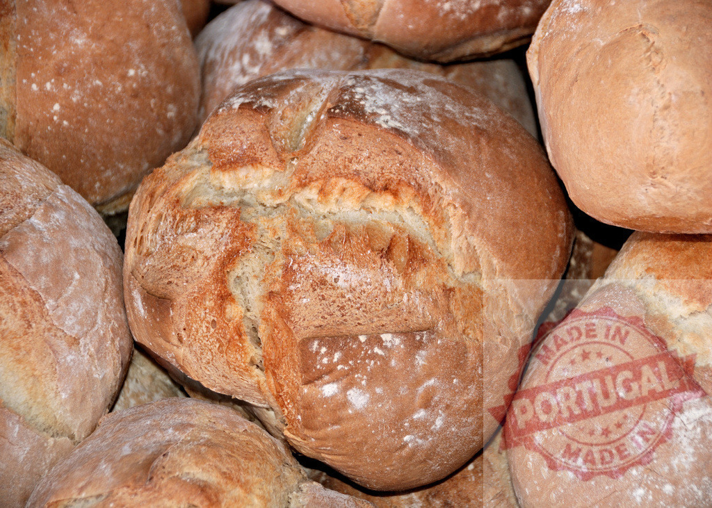 Freshly baked artisan bread loaves in a bakery | Warm, golden-brown artisan bread loaves piled high, dusted with flour - Realisiert mit Pictrs.com