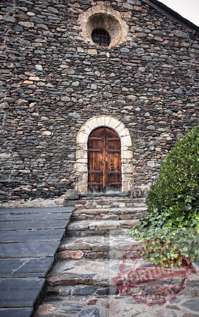 Old stone church with wooden door and stairway | Ancient stone church building featuring an arched wooden door and rustic stone steps - Realisiert mit Pictrs.com