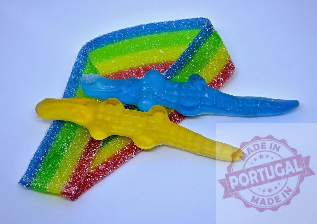 Gummy crocodiles swimming on rainbow sour candy belt | Gummy crocodiles resting on a colorful rainbow sour candy belt with sugar crystals - Realized with Pictrs.com