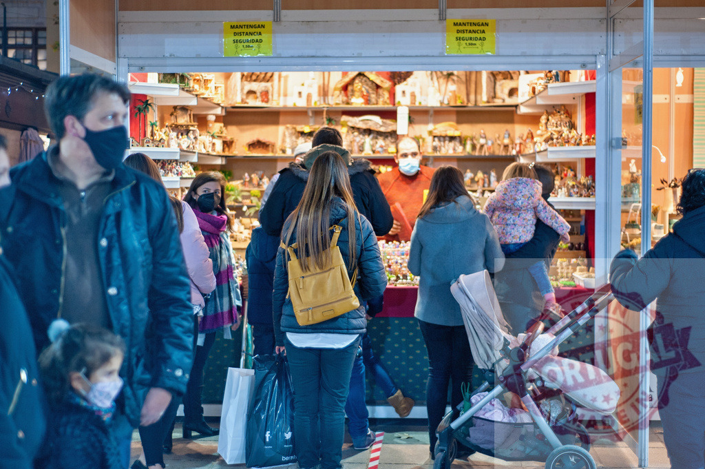 People wearing face masks shopping for Christmas market nativity scenes | Shoppers wearing face masks browsing a stall selling nativity scene figurines at a Christmas market - Realisiert mit Pictrs.com