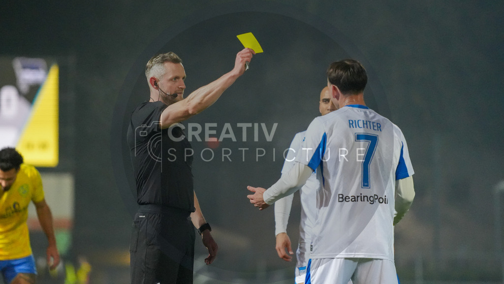 Fußball, Herren, Saison 2025/2026, Regionalliga Nordost, 15. Spieltag, FSV 63 Luckenwalde vs. Hertha BSC II, Freitag 07.11.2025, Werner-Seelenbinder-Stadion Luckenwalde, | Fußball, Herren, Saison 2025/2026, Regionalliga Nordost, 15. Spieltag, FSV 63 Luckenwalde vs. Hertha BSC II, Freitag 07.11.2025, Werner-Seelenbinder-Stadion Luckenwalde, Im Bild: Schiedsrichter Florian Markhoff (l.) zeigt Joel Richter (r. Hertha) die gelbe Karte. - Realisiert mit Pictrs.com