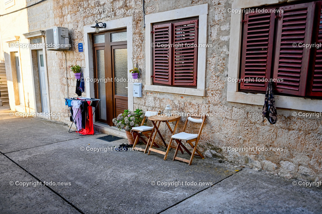Kroatien_ Supetar_ Brac_ 03.08.2023-1 | 03.08.2023, Kroatien, HRV, Brač, Insel in Dalmatien, Supetar im Bild Strasse, Gasse, Haus, Stuehle, Tisch