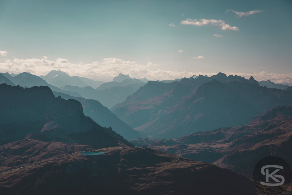 Blick vom Großen Widderstein Richtung Tirol - Alpenpanorama Vorarlberg | Spektakuläres Bergpanorama vom Gipfel des Großen Widdersteins mit Blick nach Tirol. Majestätische Alpenketten in atmosphärischen Dunstschichten, dramatische Gebirgszüge und weite Täler vereinen sich zu einem eindrucksvollen Weitblick über die Alpen. - Realisiert mit Pictrs.com