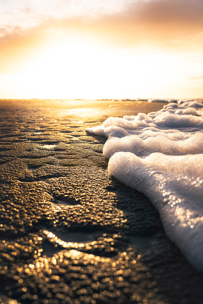 Goldene Brandung | Wenn das Licht der tief stehenden Sonne auf die feinen Strukturen des feuchten Sandes trifft und die Gischt am Ufer in Goldtöne taucht, entsteht Magie im Kleinen. Eine Momentaufnahme voller Wärme, Ruhe und Poesie. - Realisiert mit Pictrs.com