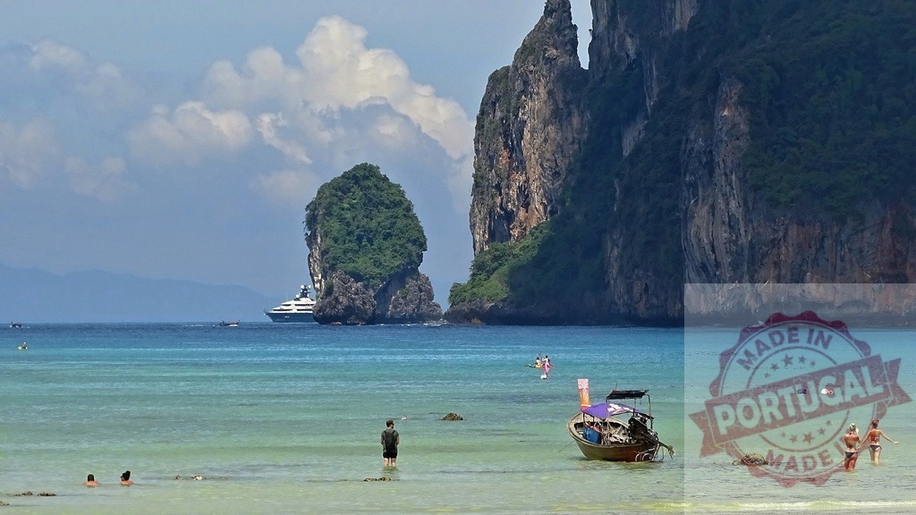 Tourists enjoying Railay Beach, Krabi, Thailand with longtail boat and luxury yacht sailing in background | Tourists enjoying the turquoise water of Railay Beach, Krabi, Thailand, with iconic longtail boat and luxury yacht sailing in the background - Realized with Pictrs.com