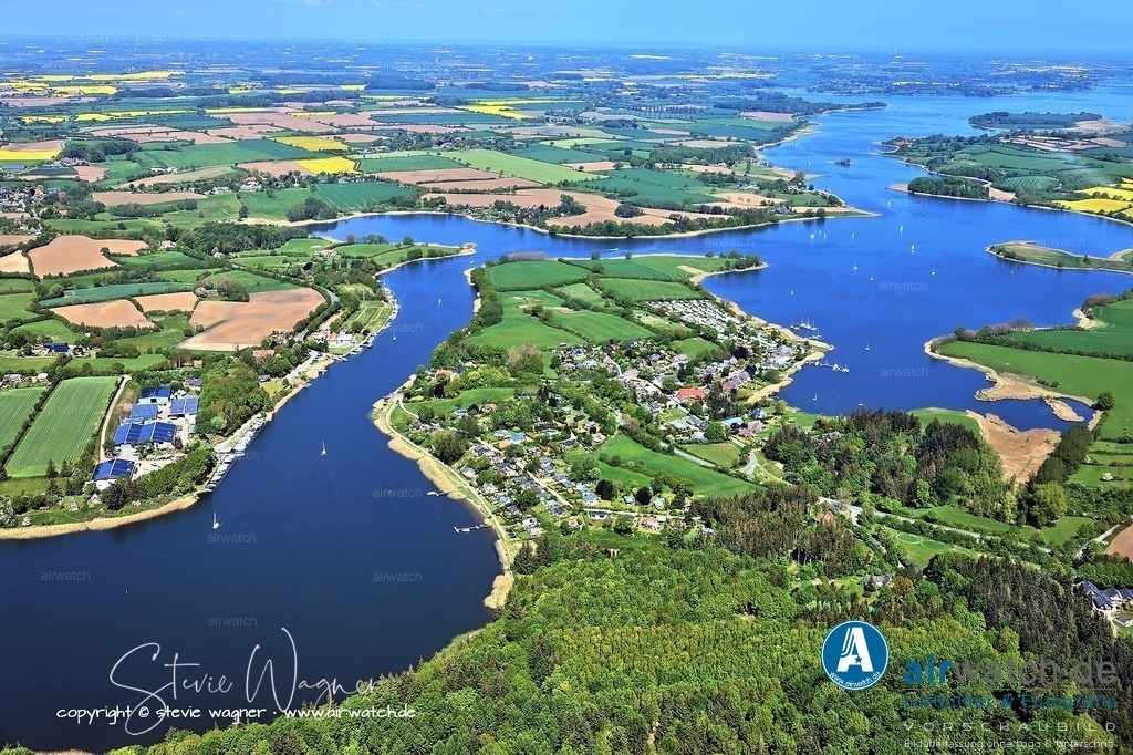 Luftbild Ostseefjord Schlei, Missunde, Campingplatz Wees, Fährhaus Missunde, Marina Brodersby | Ostseefjord Schlei: Die Fähre, die seit 2003 als Schleifähre Missunde II im Einsatz ist, gleitet an einem Drahtseil über die Schlei und kann maximal 45 Personen transportieren. Sie verkehrt wochentags von 6 bis 22 Uhr und am Wochenende von 8 bis 22 Uhr, mit eingeschränktem Betrieb an Heiligabend bis 18 Uhr und einem späteren Start am Neujahrstag um 10 Uhr. Ab Ende 2025 ist die Einführung einer neuen Elektrofähre geplant, die die aktuelle Fähre ersetzen soll.