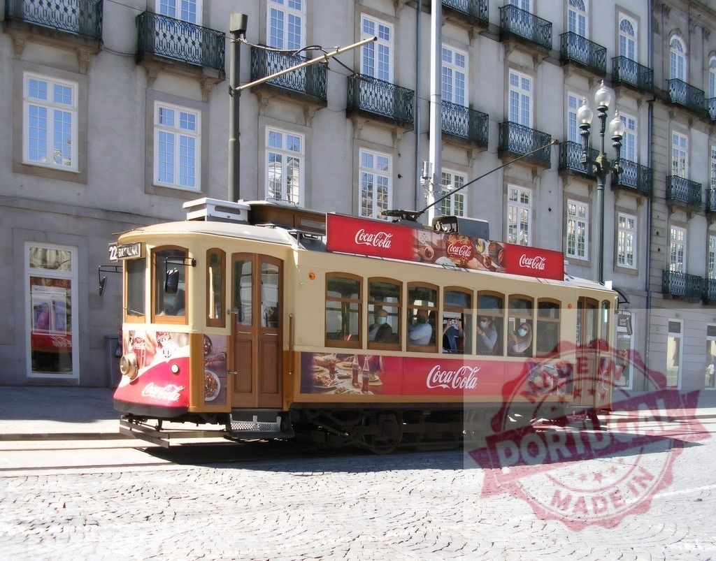 Vintage tram moving on cobblestone streets of Porto | Vintage tram displaying Coca-Cola branding moving along a street in Porto, Portugal - Realized with Pictrs.com