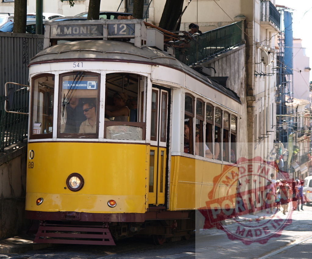 Yellow Tram Ascending a Steep Street in Lisbon, Portugal | Passengers enjoying a ride on a vintage yellow tram climbing a hill in Lisbon, Portugal, a popular tourist attraction - Realized with Pictrs.com