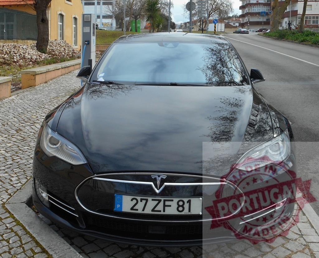 Tesla Model S electric vehicle charging on street | Black Tesla Model S car connected to an electric charging station on a city street - Realisiert mit Pictrs.com