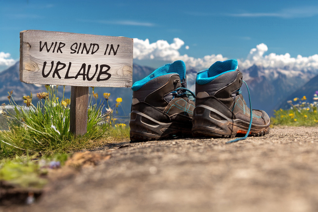 Symbolbild Betriebsferien/Sommerferien: Wanderschuhe vor alpiner Kulisse und Schild mit der Aufschrift WIR SIND IN URLAUB | Symbolbild Betriebsferien/Sommerferien: Wanderschuhe vor alpiner Kulisse und Schild mit der Aufschrift WIR SIND IN URLAUB - Realisiert mit Pictrs.com
