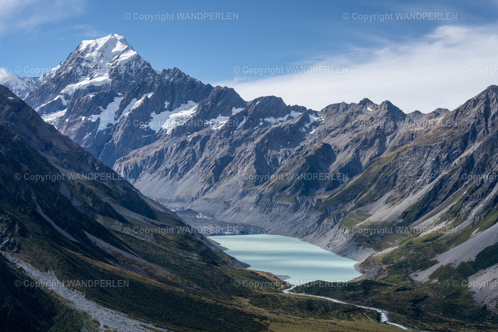 Mount Cook | Ein atemberaubendes Luftbild zeigt den majestätischen Aoraki / Mount Cook, Neuseelands höchsten Berg, der scharf gegen einen klaren blauen Himmel aufragt. Darunter liegt ein türkisfarbener Gletschersee in einer tiefen Schlucht, flankiert von steilen, felsigen Hängen. Die Szene betont die raue Schönheit der Südlichen Alpen, mit schneebedeckten Kanten, freiliegenden Felsen und Gletschermoränen. Das Bild wurde von einer erhöhten Position aus aufgenommen, um einen weiten Blick auf diese ikonische Alpenlandschaft zu ermöglichen. - Realisiert mit Pictrs.com