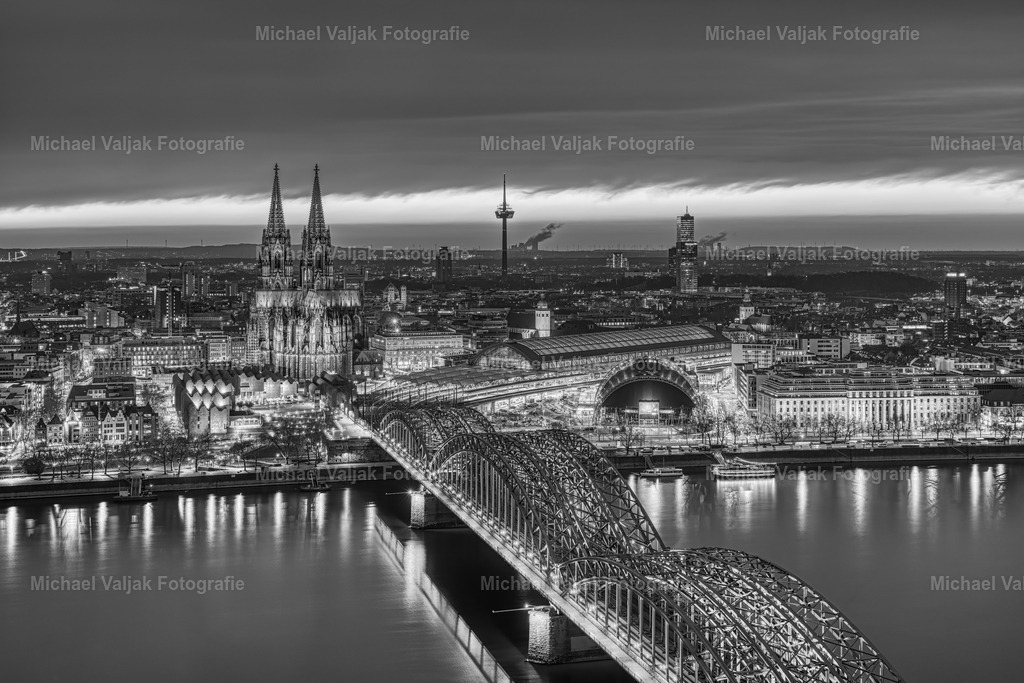 Köln bei Nacht in schwarz-weiß | Blick über die Kölner Innenstadt mit dem Kölner Dom, der Hohenzollernbrücke und dem Musical Dome als markante Sehenswürdigkeiten. Zuvor gab es einen fantastischen Sonnenuntergang, der bis in die Nacht hineinleuchtete. Eine ganz besondere Stimmung hoch über den Dächern Kölns, hier in einer Schwarz-Weiß-Version. - Realisiert mit Pictrs.com
