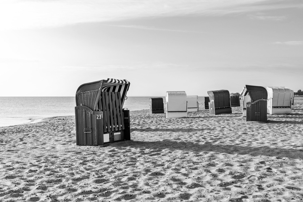 Wandbild: Strandkörbe am Weidefelder Strand in Schwarz-Weiß | Dieses Wandbild im Querformat zeigt den Strand in Weidefeld in Schwarz-Weiß. Am Strand stehen zahlreiche Strandkörbe. - Realisiert mit Pictrs.com
