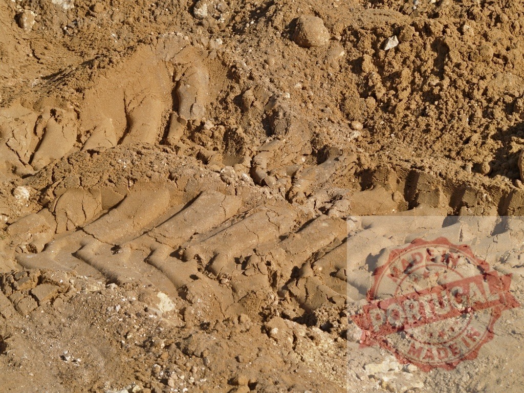Tire tracks creating pattern on sand surface in construction site | Close-up of tire tracks imprinted on a sand surface, possibly indicating recent activity at a construction or industrial site - Realized with Pictrs.com