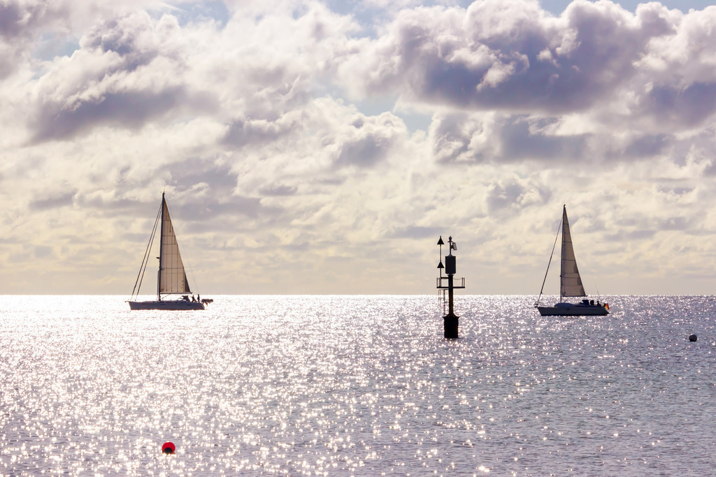 Wandbild: Segelträume – Lichtspiel auf der Ostsee | Holen Sie sich das Gefühl von Freiheit und Meeresbrise direkt in Ihr Wohnzimmer. Dieses eindrucksvolle Wandbild fängt den Zauber eines glitzernden Tages auf der See ein, während Segelboote majestätisch durch das funkelnde Gegenlicht gleiten. Das Spiel aus Licht und Schatten auf den Wellen und die imposante Wolkenkulisse verleihen dem Motiv eine lebendige Tiefe. Ein ideales Kunstwerk für alle Segelliebhaber und Küstenkinder, das Fernweh weckt und eine inspirierende, weite Atmosphäre in Ihr Zuhause bringt. - Realisiert mit Pictrs.com