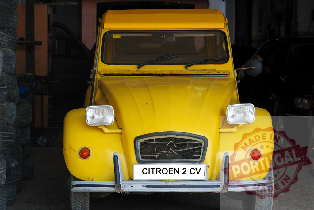 Classic yellow Citroën 2 CV parked in garage showing its front | Front view of a vintage yellow Citroën 2 CV parked inside a garage - Realisiert mit Pictrs.com