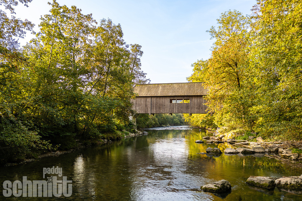 Alte historische Holzbrücke über die Argen | Eine alte historische Holzbrücke über die Argen, eingebettet in die idyllische Natur des Allgäus. Das traditionelle Bauwerk fügt sich harmonisch in die ruhige und ursprüngliche Flusslandschaft ein. - Realisiert mit Pictrs.com